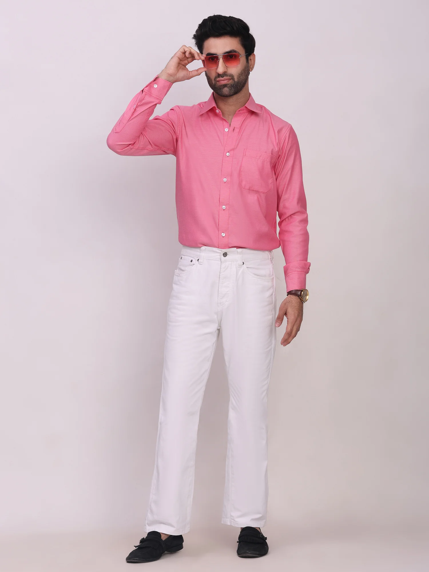 Front view of a model wearing a pink long-sleeve shirt with a front pocket and white trousers