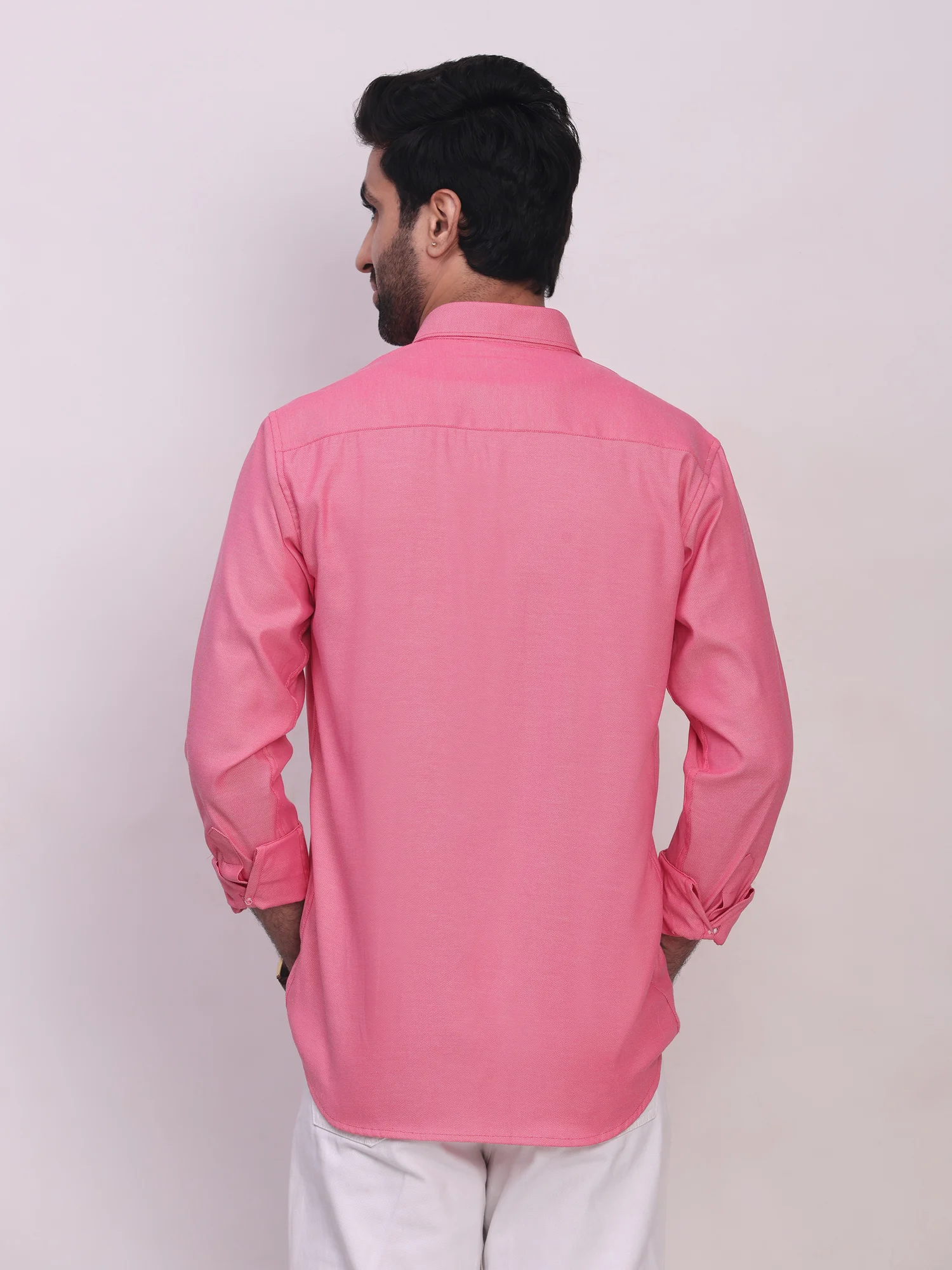 Back view of a model wearing a plain pink long-sleeve shirt with a collar