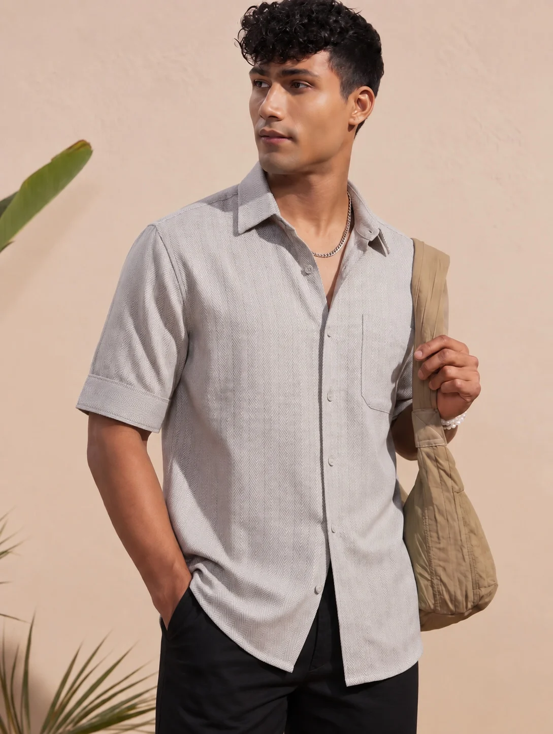 Model wearing a taupe short-sleeve chevron shirt with a spread collar and chest pocket
