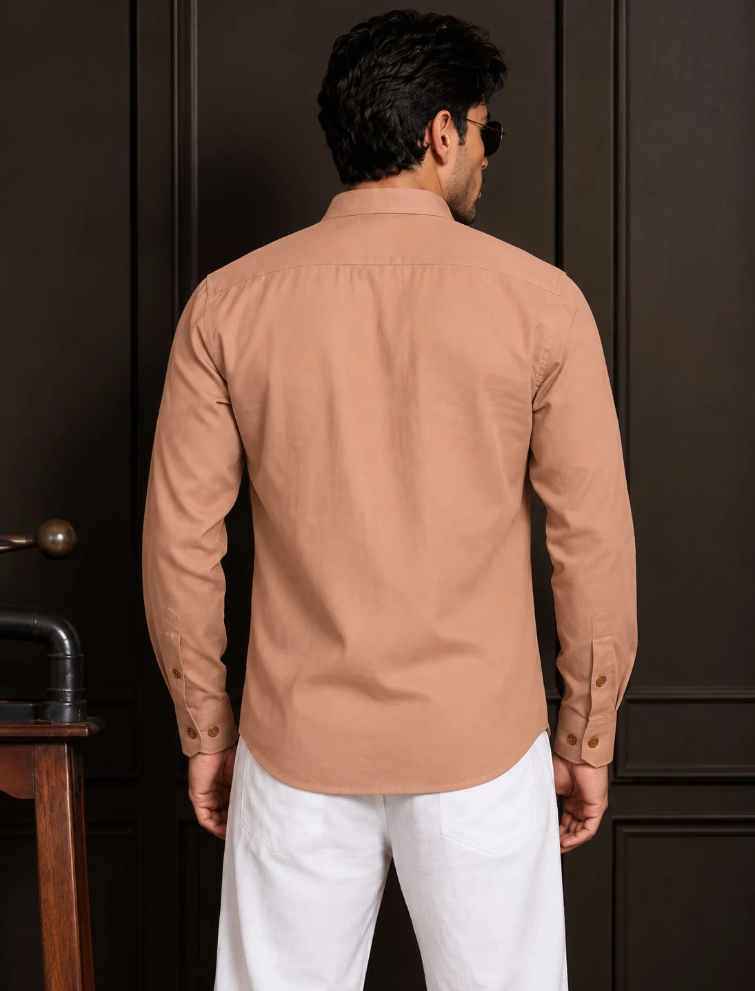 Back view of a model wearing a peach long-sleeve shirt with a collar and white trousers