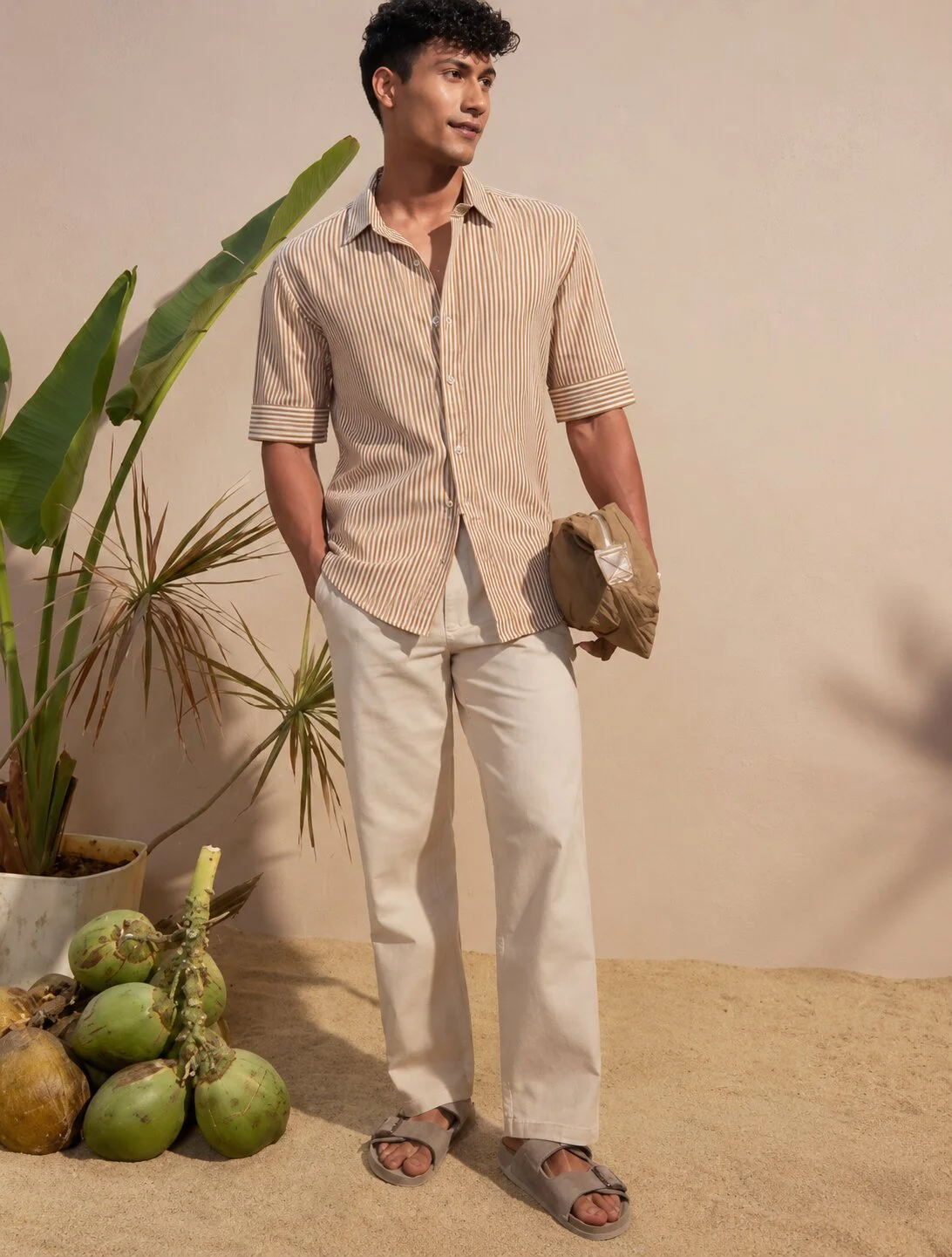 Striped beige short-sleeved shirt, worn by a model, buttoned collar, cuffs, pockets