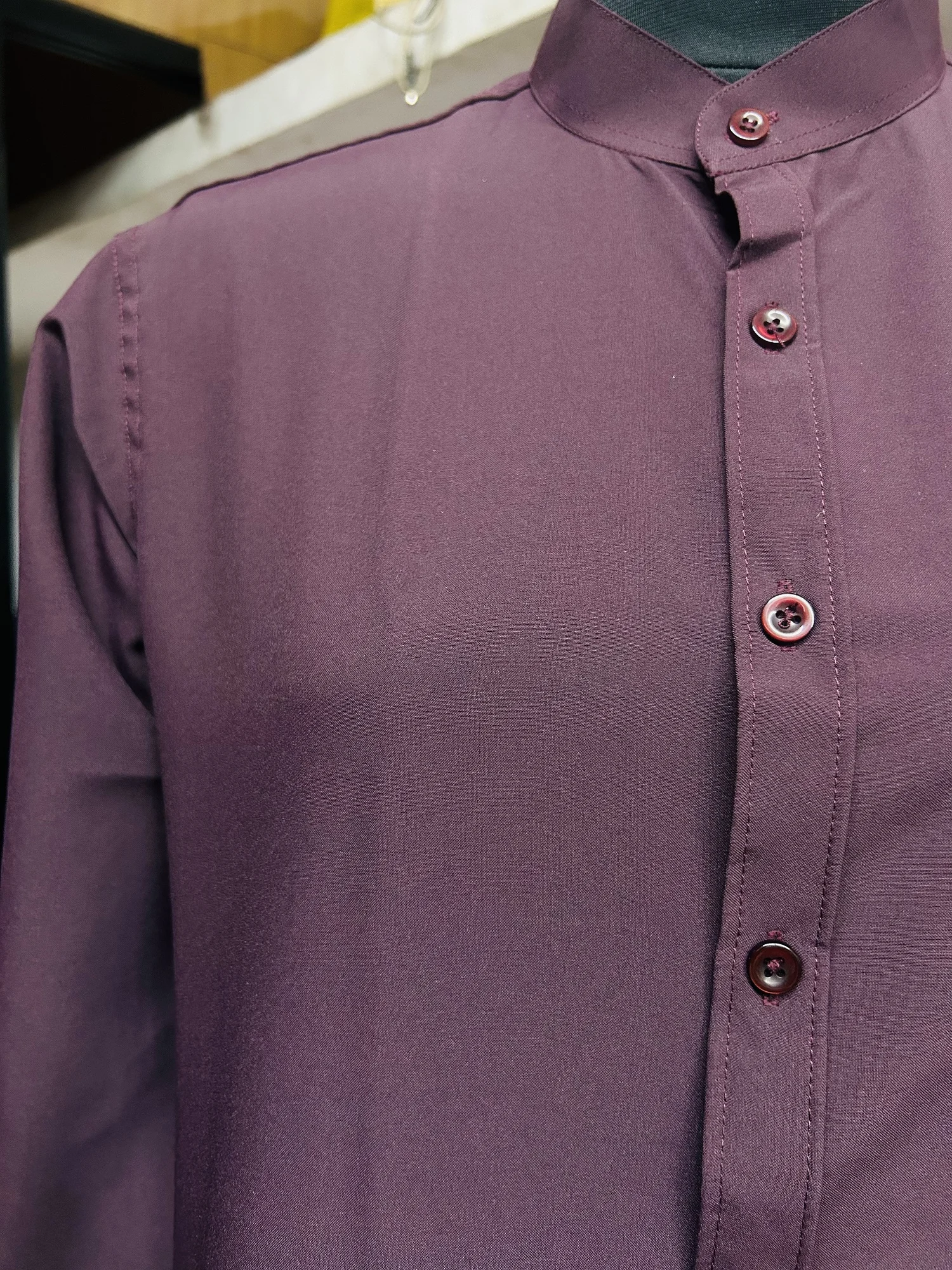Close-up of a wine purple shirt kurta on a mannequin, showing the mandarin collar and front button placket