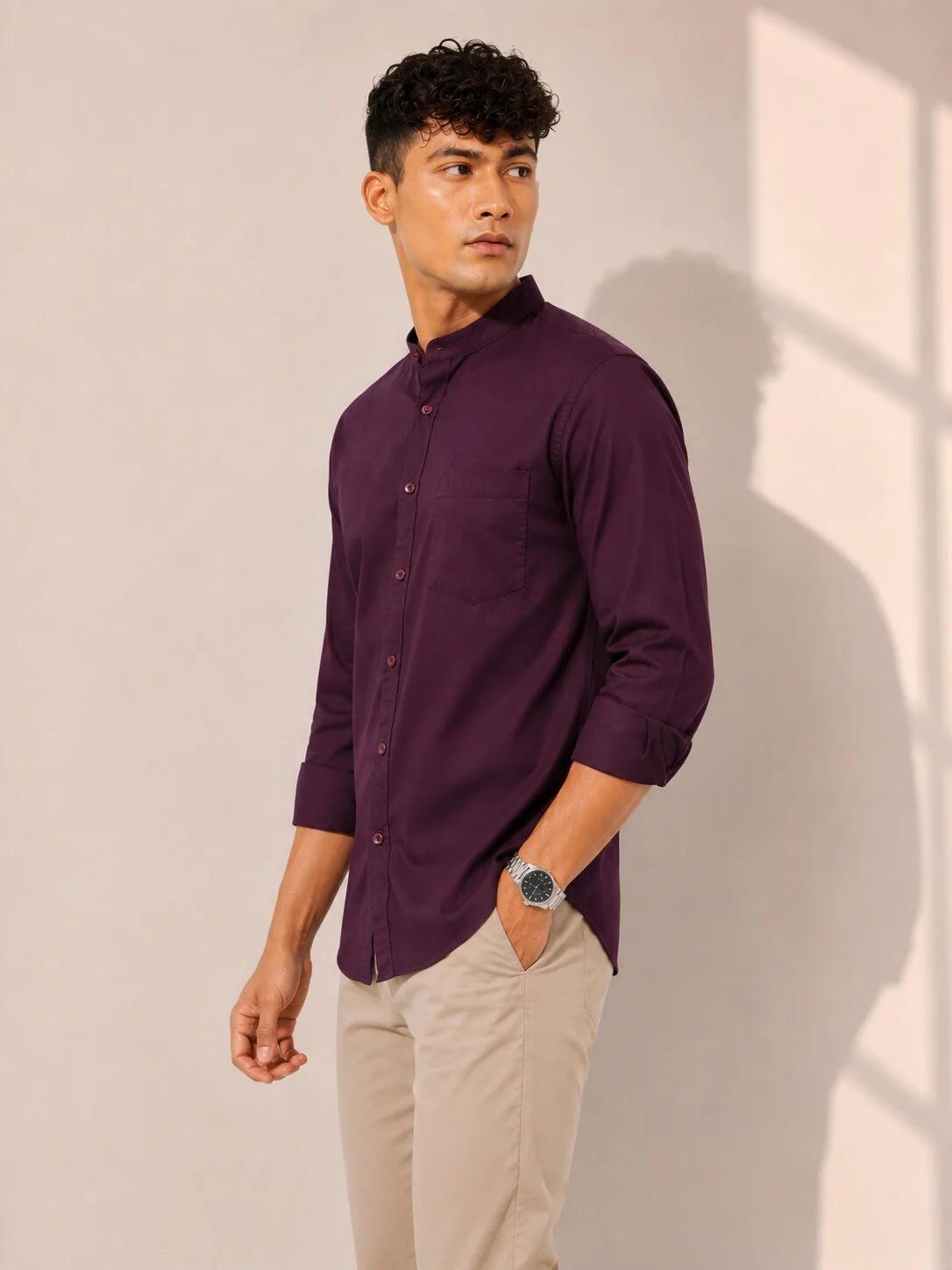 Model wearing wine purple short kurta with mandarin collar, chest pocket, and rolled-up sleeves, side view