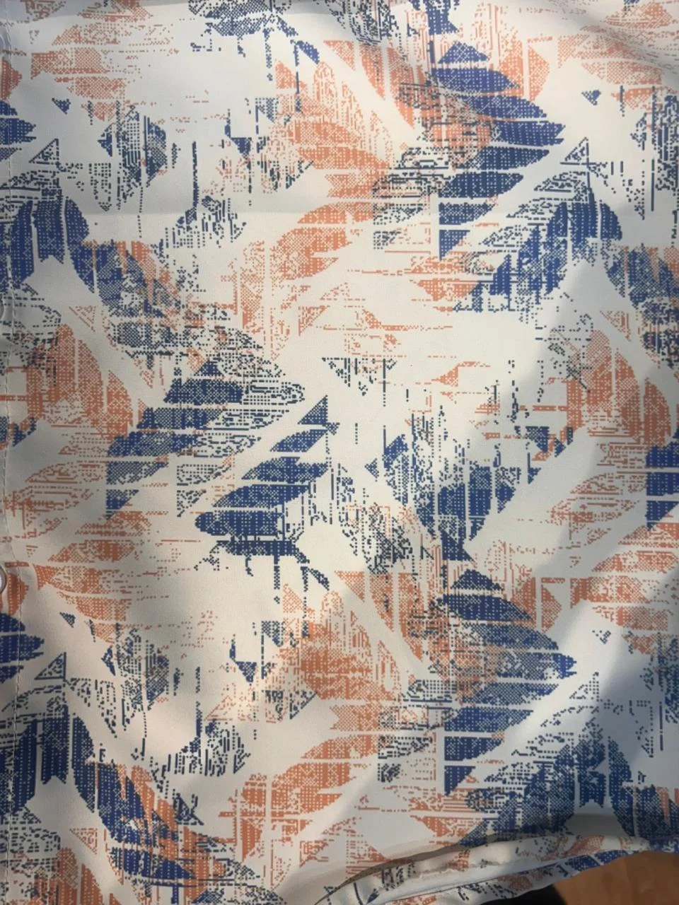 Abstract printed fabric, white base with blue and orange pattern, flat lay