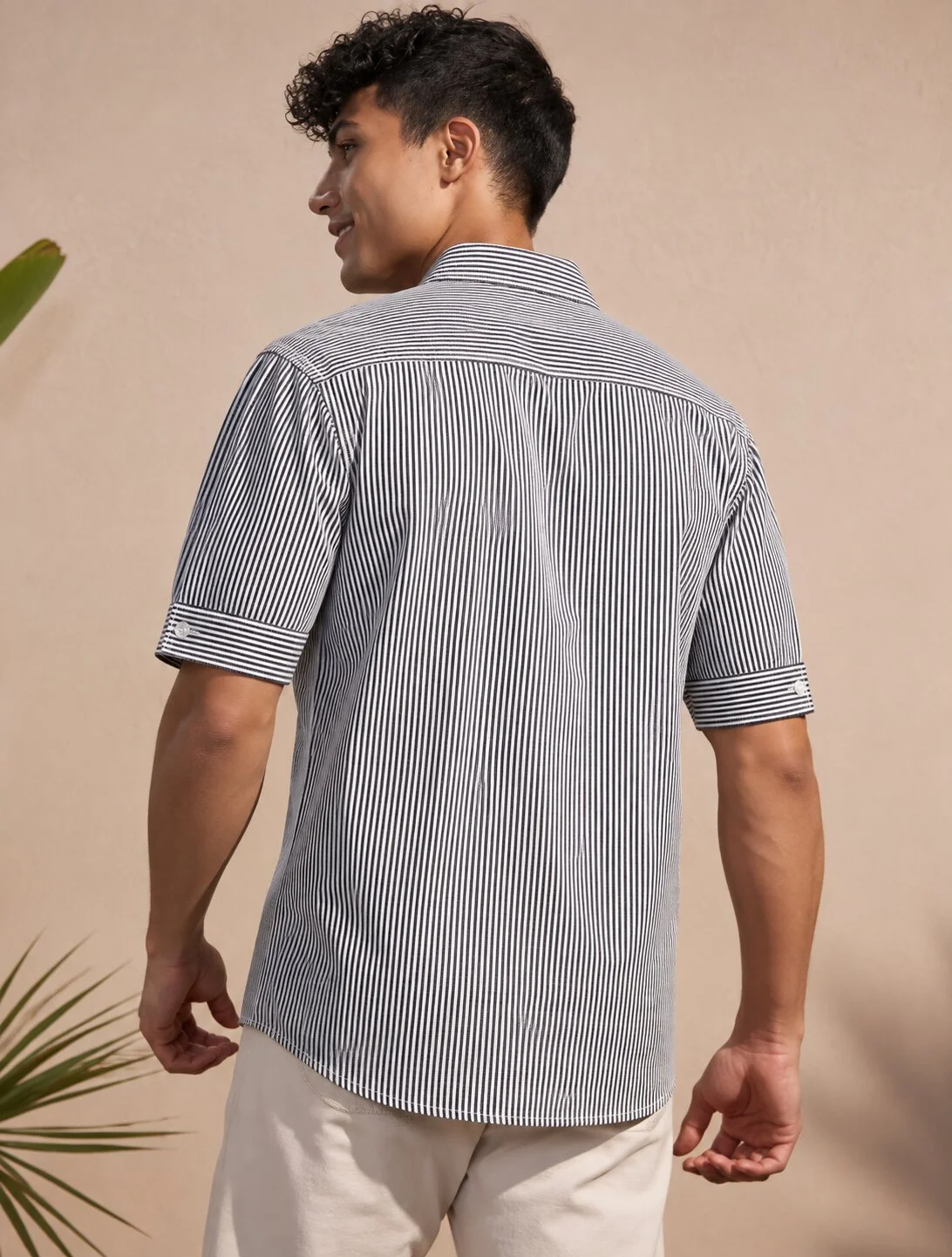 Short-sleeved shirt, black and white stripes, back view, worn by a model