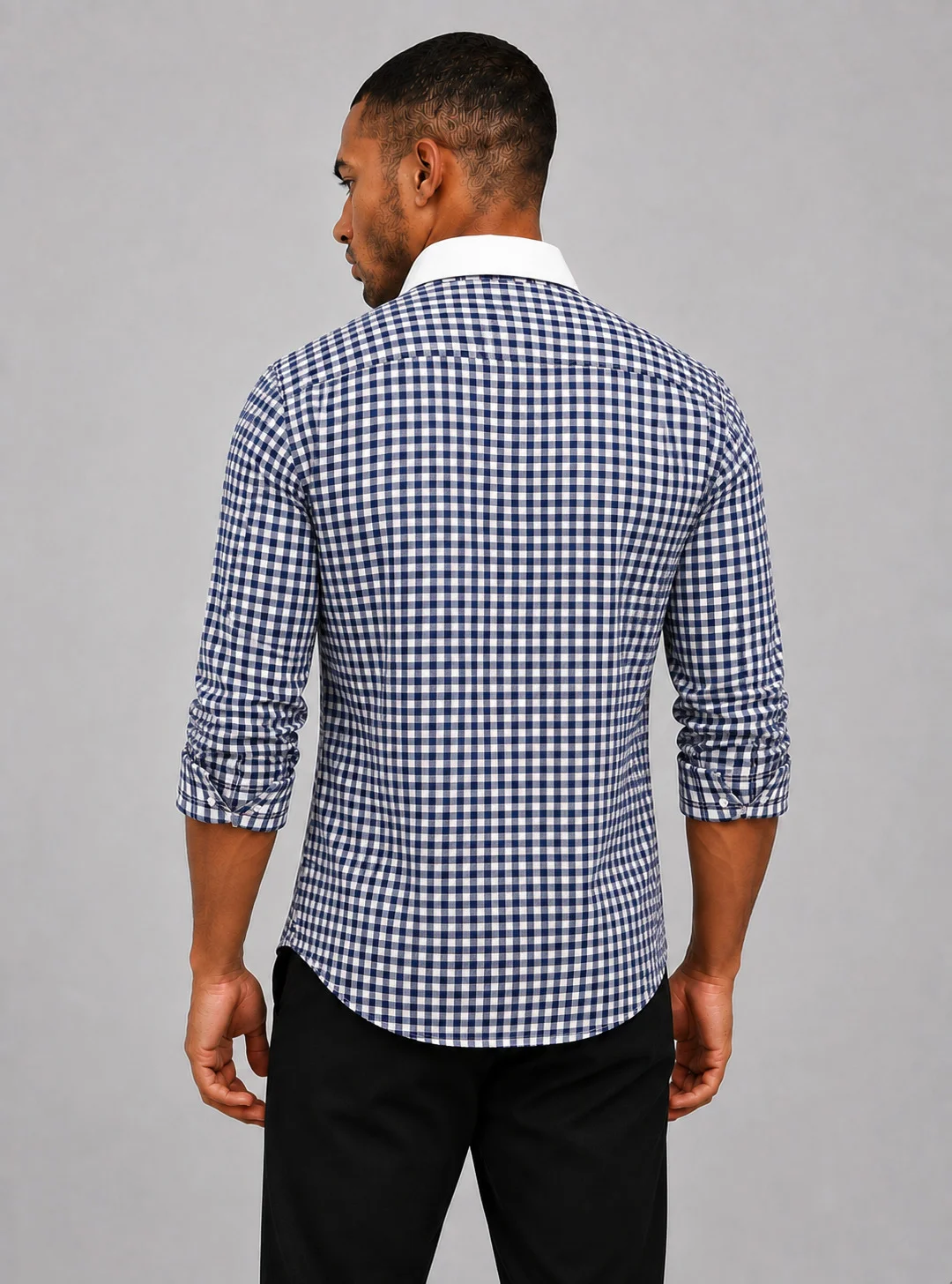 Back view of a man wearing a blue and white checkered shirt with long sleeves and a white collar