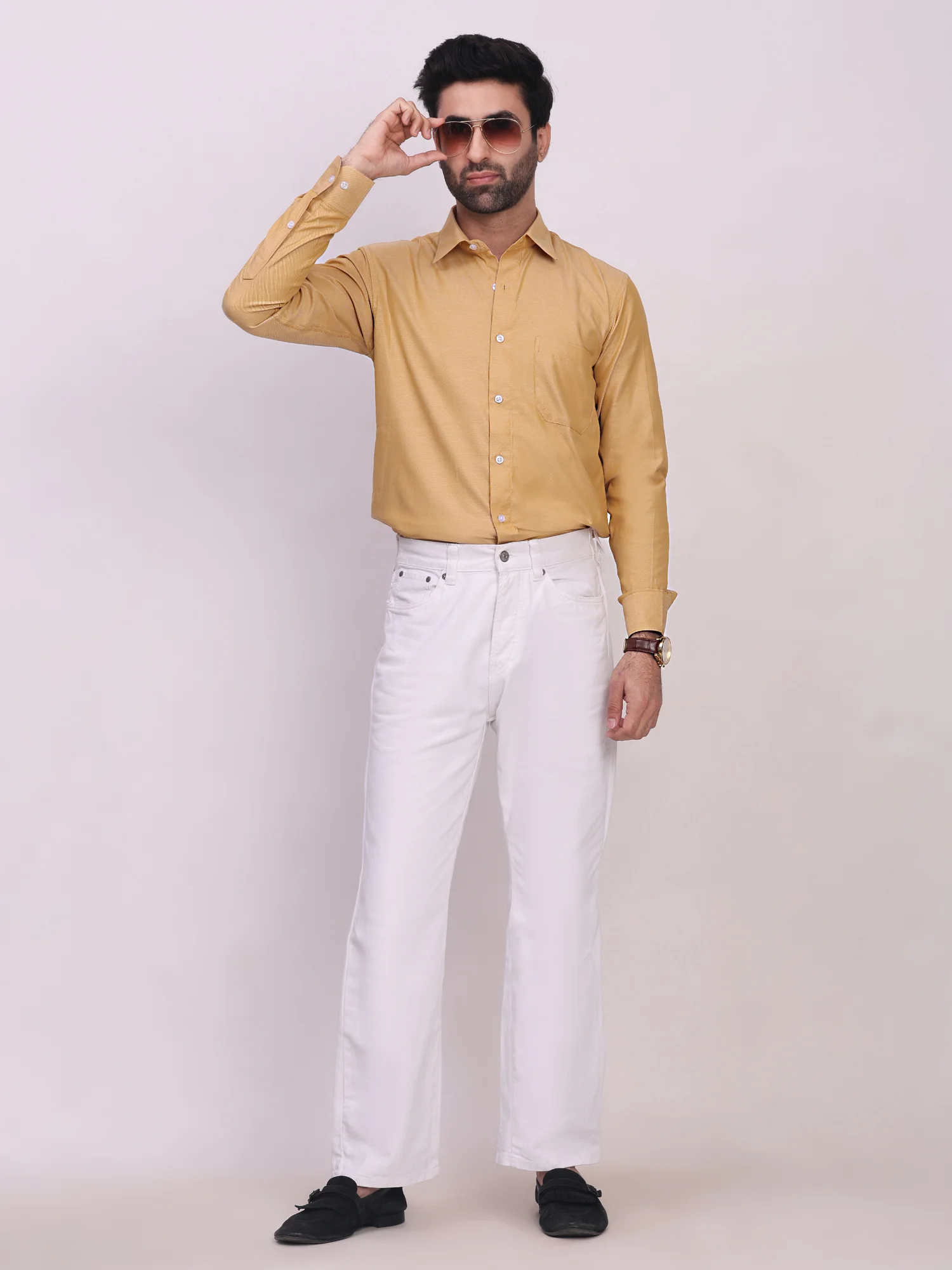 Model wearing golden yellow long sleeve shirt with shirt collar and white trousers, front view