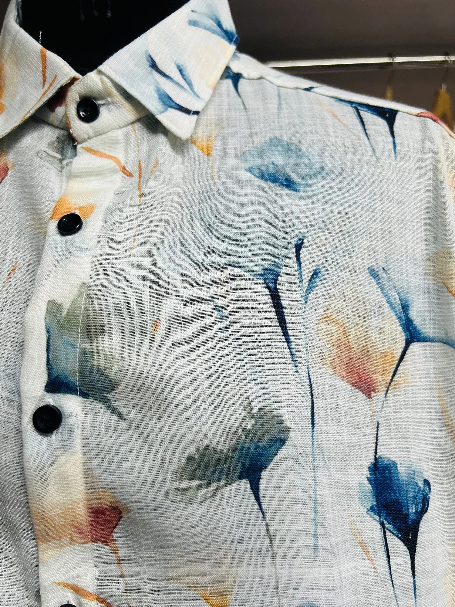 White shirt, floral pattern, black buttons, collar visible, close-up view