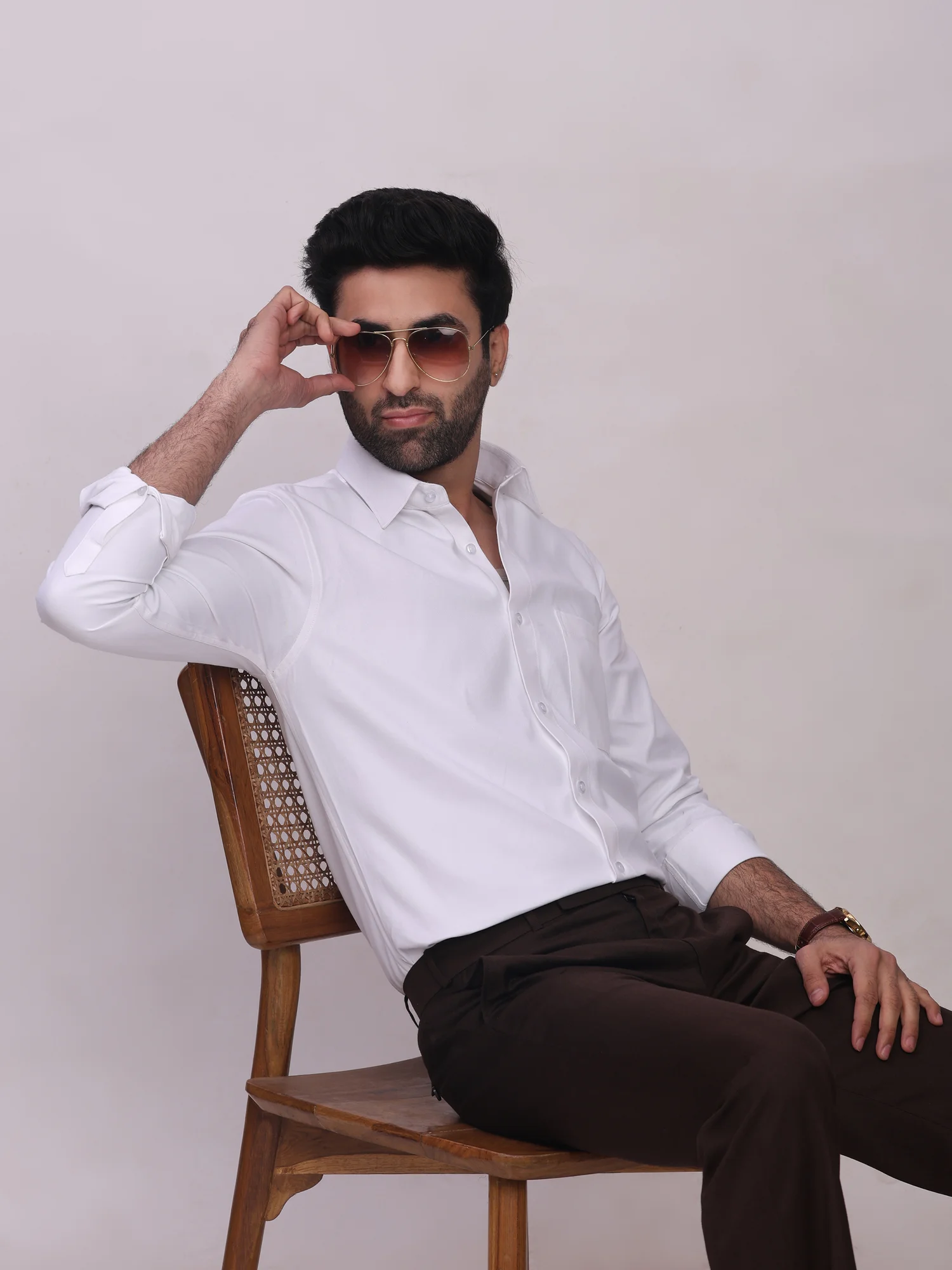 Model sitting on a chair wearing a solid white shirt with long sleeves and collar
