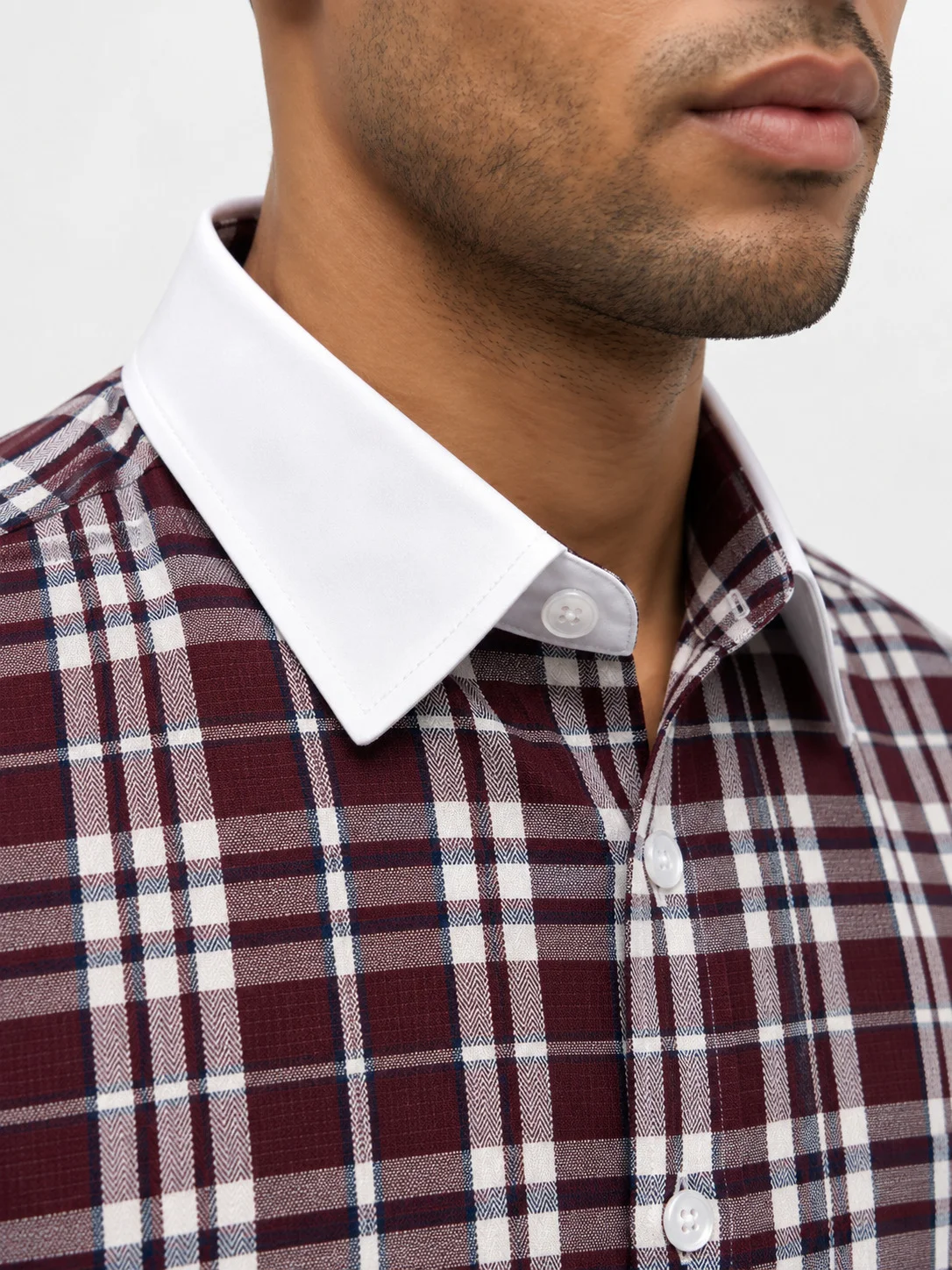 Close-up of a model wearing a maroon and white checked shirt with a contrasting white collar and front buttons