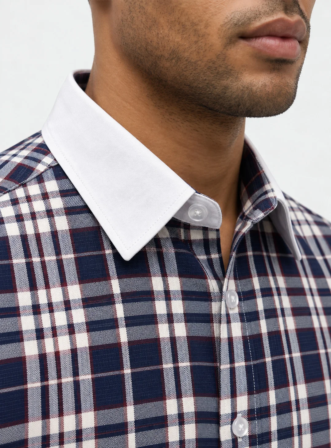 Close-up of a model wearing a navy blue checked shirt with a white pointed collar and front buttons