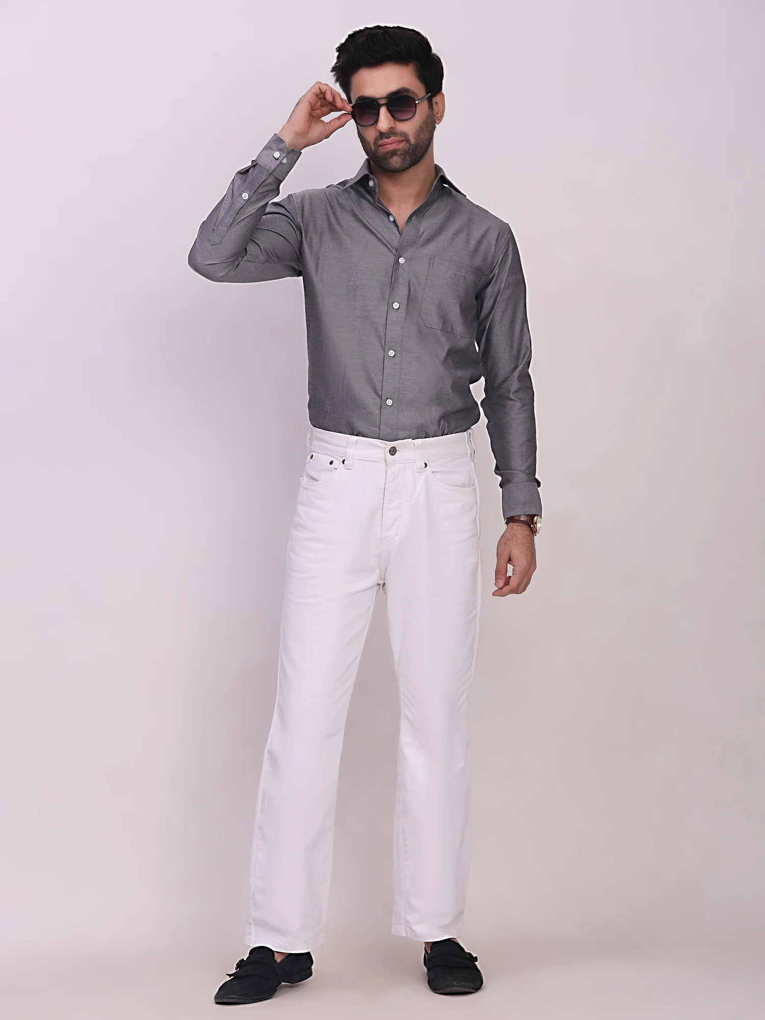 Front view of a model wearing a grey full-sleeve shirt with a front pocket, collar, and buttons, paired with white trousers