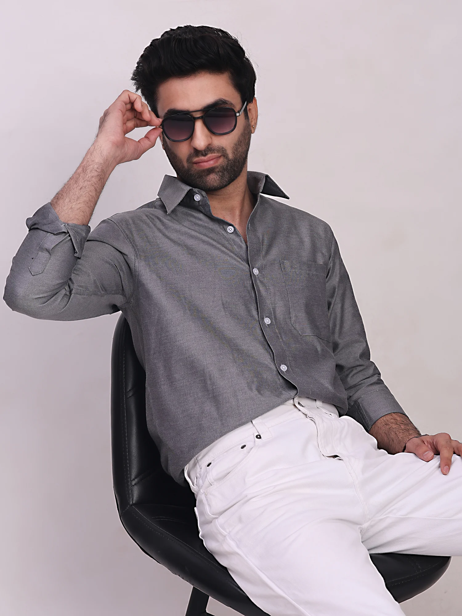 Front view of a model wearing a grey full-sleeve shirt with collar and pocket, paired with white trousers