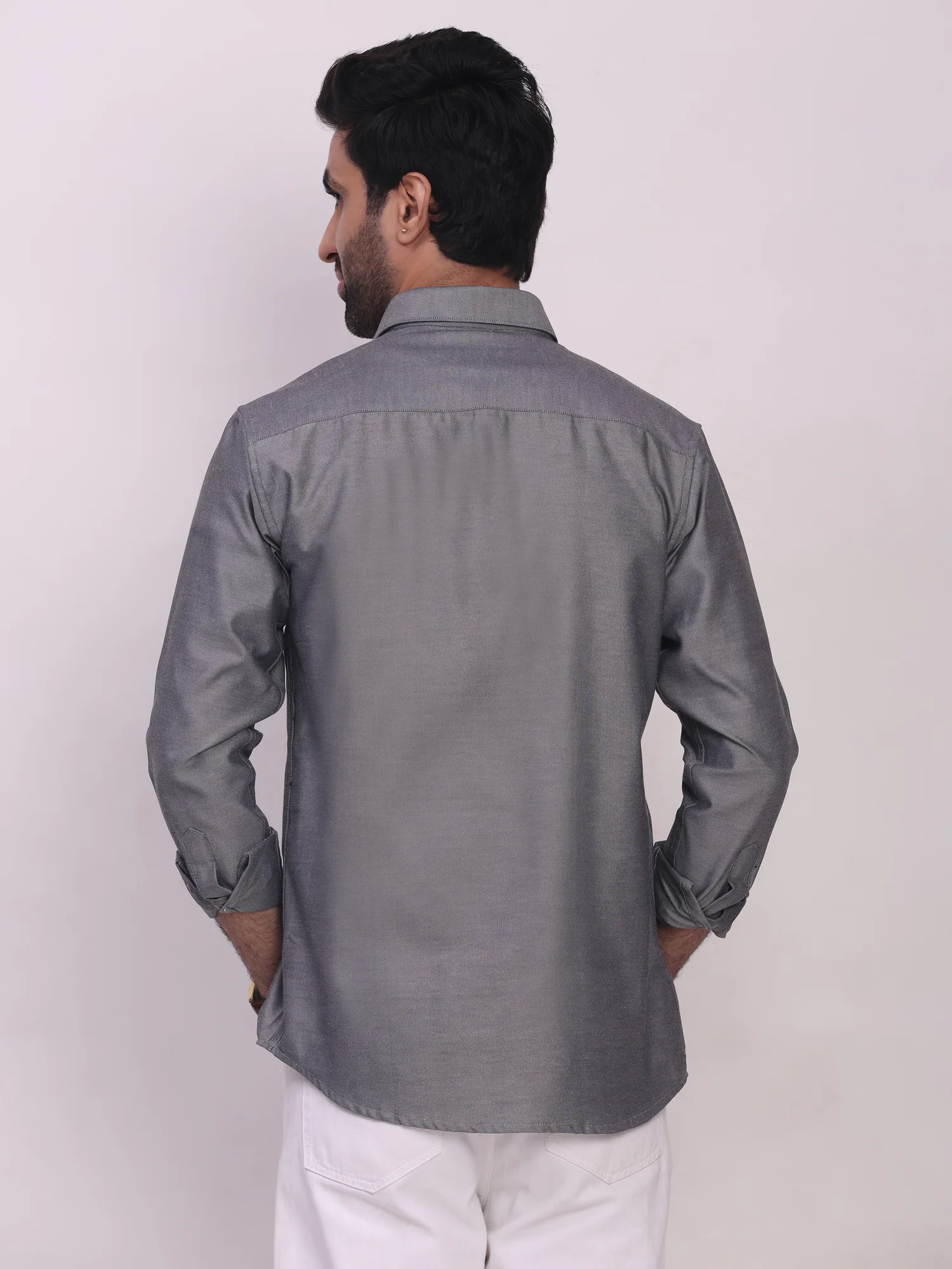 Back view of a model wearing a plain grey long-sleeve shirt with a collar and white trousers