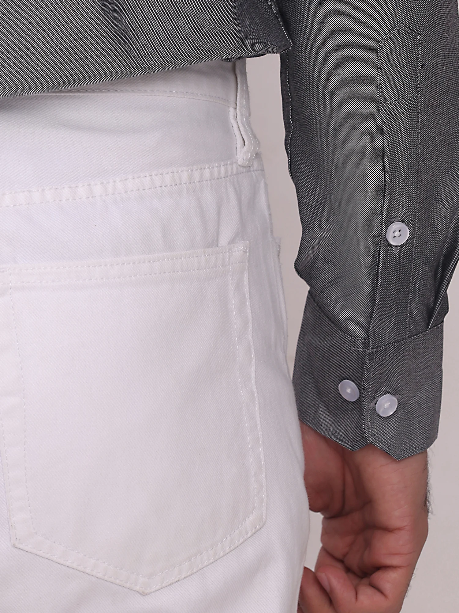 Close-up of a grey long-sleeved shirt cuff with buttons worn by a model