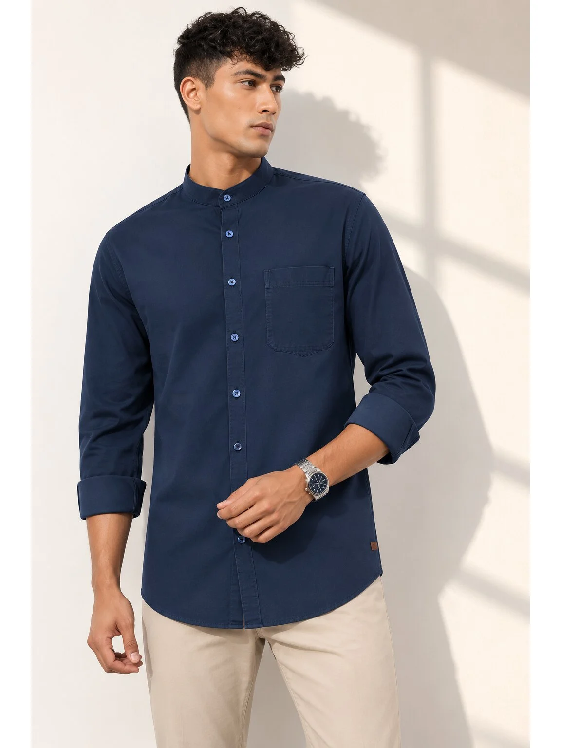 Navy blue kurta with mandarin collar, buttons, chest pocket, and rolled-up sleeves, worn by a model
