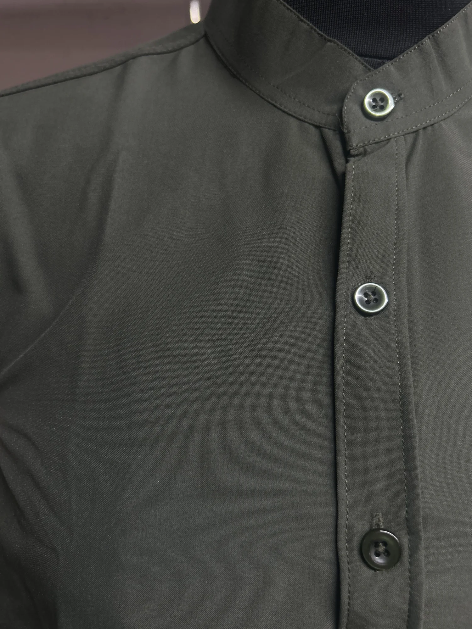 Close-up of a dark olive green shirt kurta showing mandarin collar and buttons