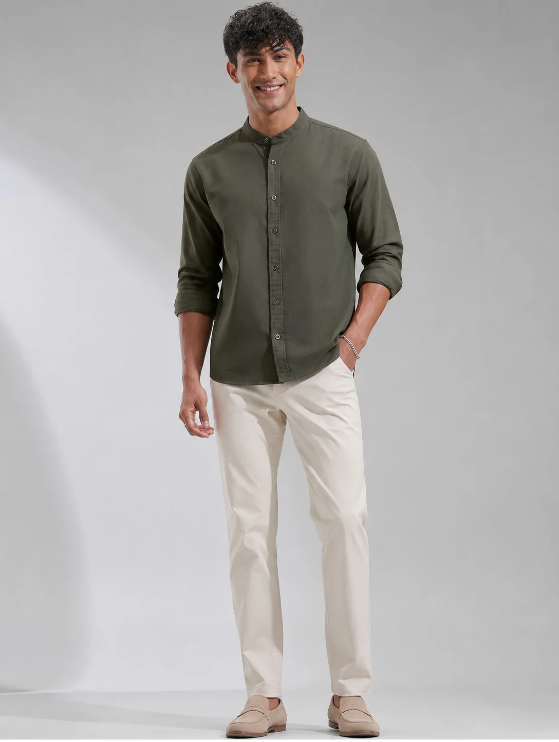 Model wearing dark olive green button-down short kurta with mandarin collar and full sleeves, front view