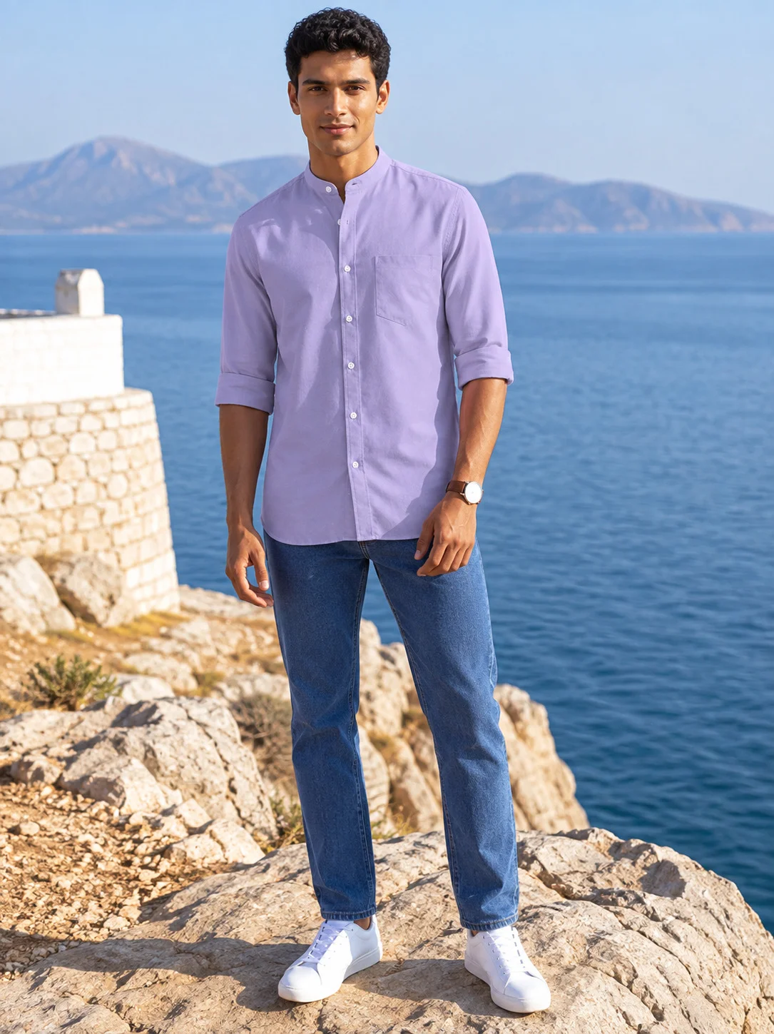 Model wearing a purple shirt kurta with mandarin collar, chest pocket, full sleeves and blue jeans against sea view