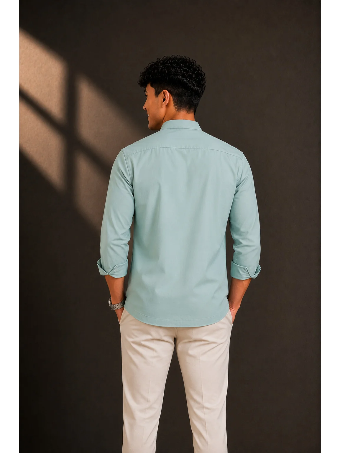 Back view of a model wearing a sea green short kurta with cuffed sleeves and light trousers
