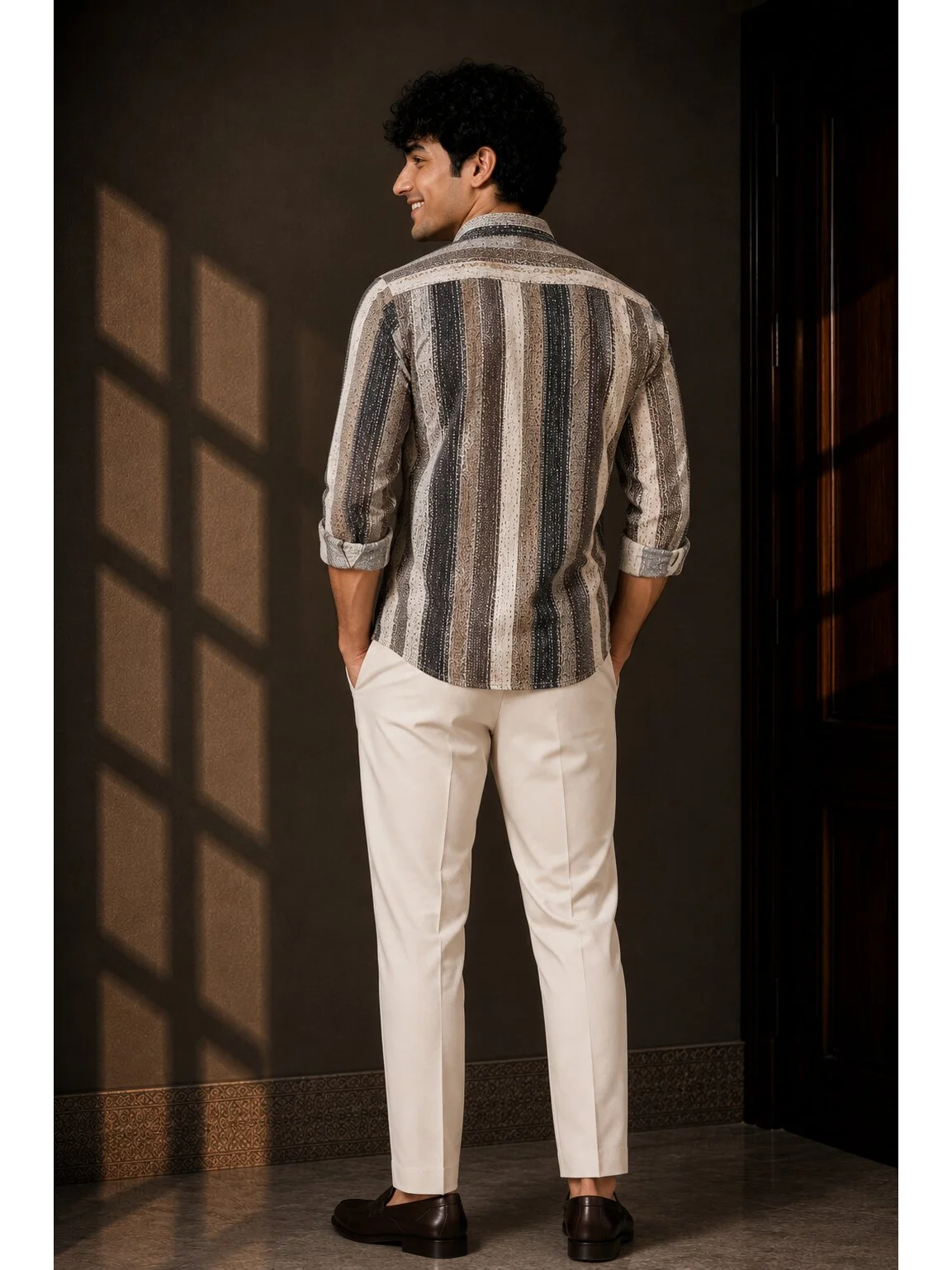 Back view of a male model wearing a striped short kurta in navy blue and off-white with off-white trousers