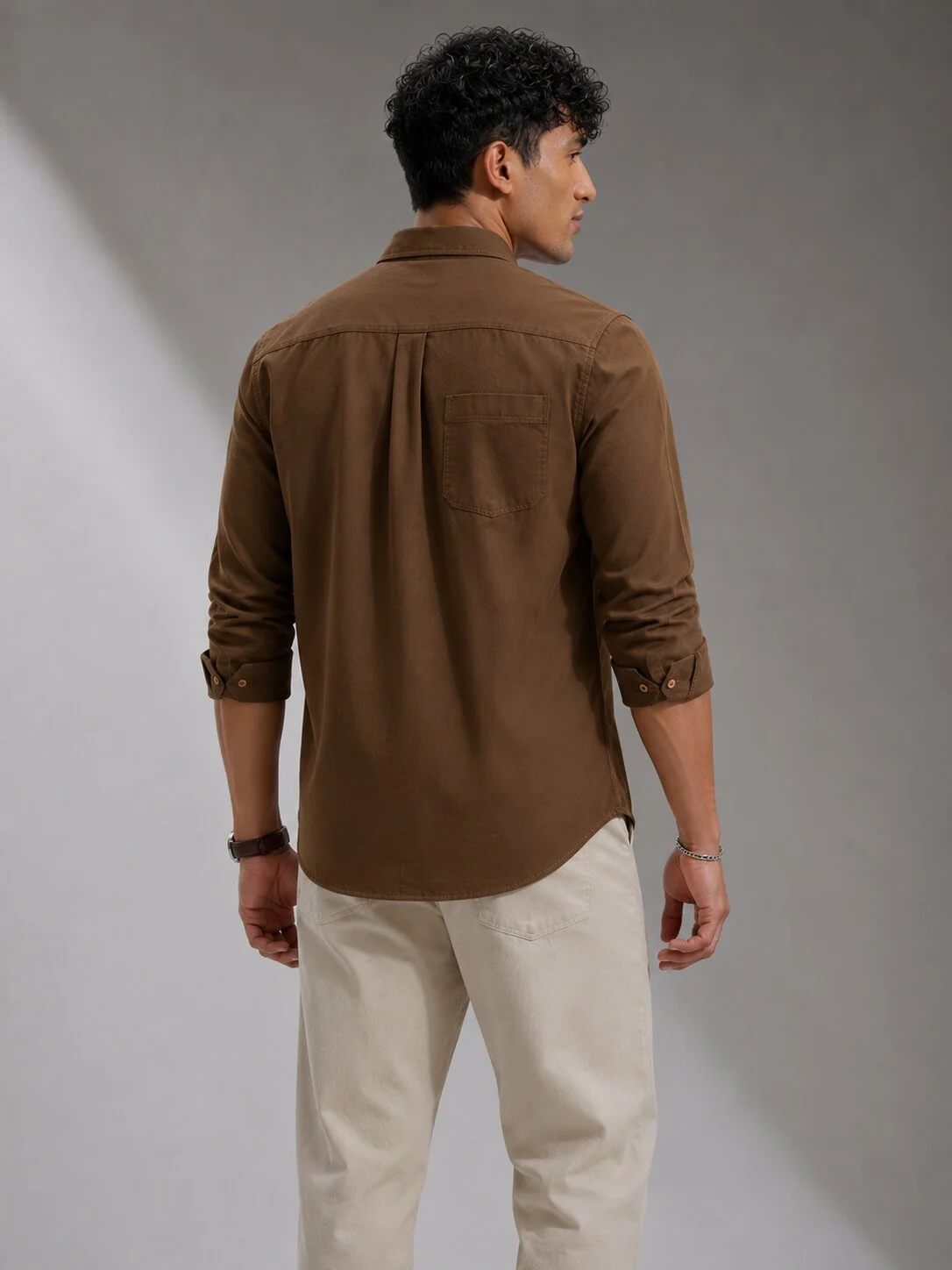 Back view of a model wearing a brown shirt with full sleeves, collar, and a chest pocket